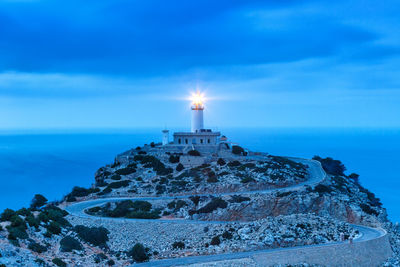 Lighthouse by sea against blue sky