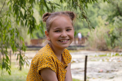 Portrait of young woman standing against tree