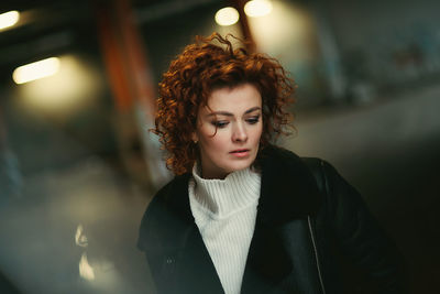 Portrait of young woman standing against wall