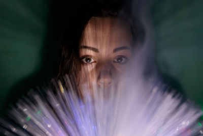 Close-up portrait of young woman holding multi colored fiber optic