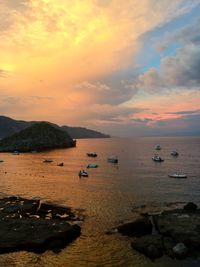 Boats in sea at sunset