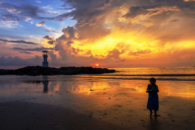 People on beach against sky during sunset