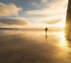 Man on beach against sky during sunset