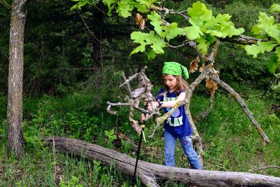 Portrait of happy girl holding plants against trees