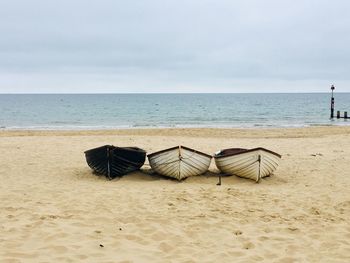 Lounge chairs on sand at beach against sky