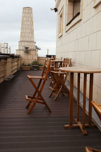 Empty chairs and tables against buildings in city