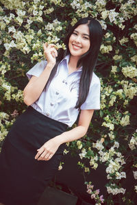 Portrait of a smiling young woman standing against plants