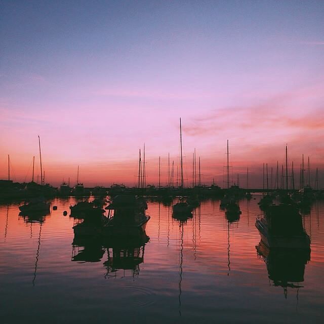 SAILBOATS MOORED IN CALM SEA AT SUNSET