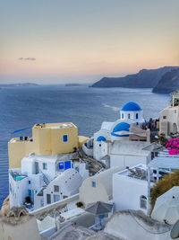 Buildings by sea against sky during sunset