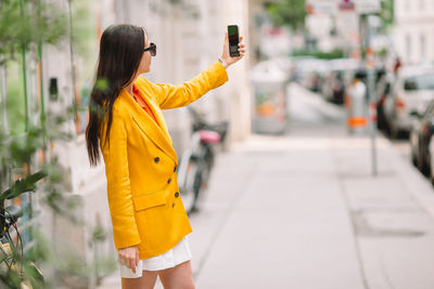 Woman photographing with umbrella standing in city