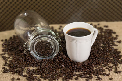 Glass jar and black coffee on coffee beans