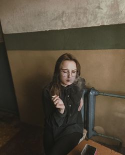 Young woman looking away while sitting on wall