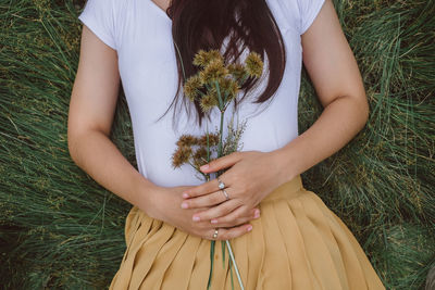 Midsection of woman holding hands on field