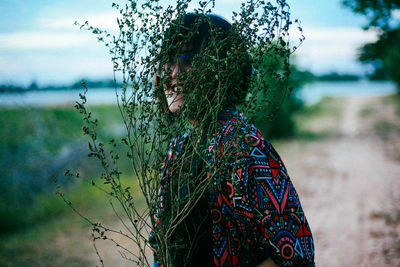 Portrait of young woman standing against sky