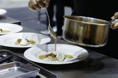 Chef cooking add sauce to  dessert dish. decorating delicious meal in restaurant kitchen for dinner.