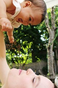 Close-up of mother lifting cheerful daughter at park