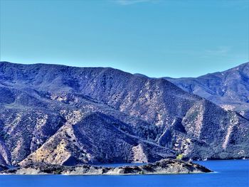 Scenic view of sea and mountains against clear blue sky