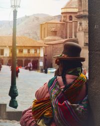 Rear view of woman with umbrella against building in city