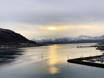 Scenic view of lake by mountains against sky during sunset
