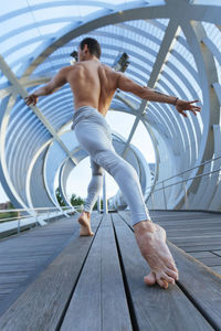 Low angle view of shirtless man dancing on bridge