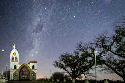 Historic church by trees against star field