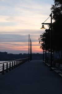 Street amidst silhouette city against sky during sunset