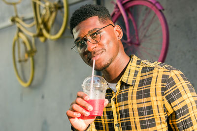 Young man drinking water against wall