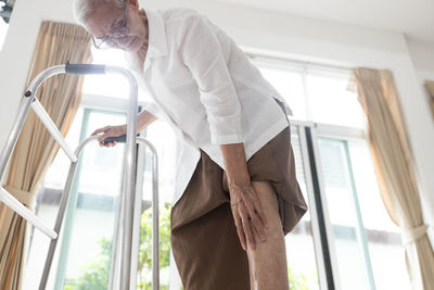 Low angle view of man standing by window at home