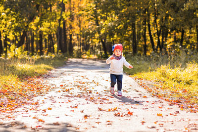 Full length of girl standing on footpath during autumn