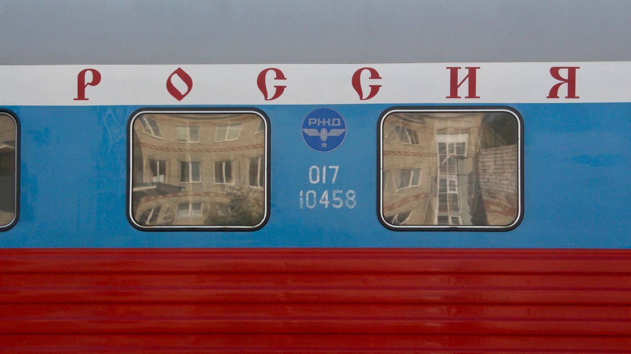 TRAIN ON RAILROAD STATION PLATFORM SEEN THROUGH GLASS WINDOW