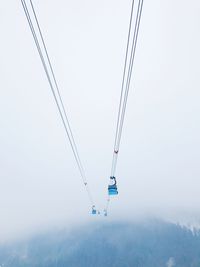 Low angle view of overhead cable car against sky