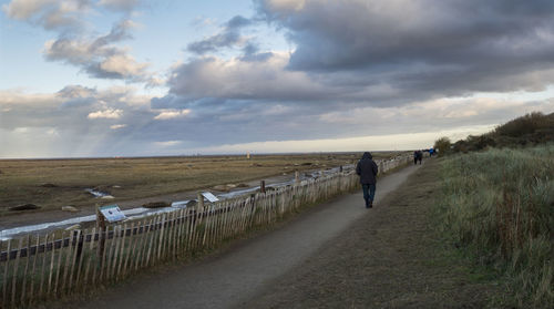 Man walking on beach against sky