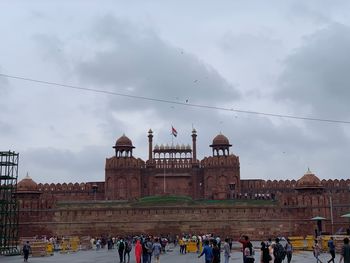 People at historic building against sky