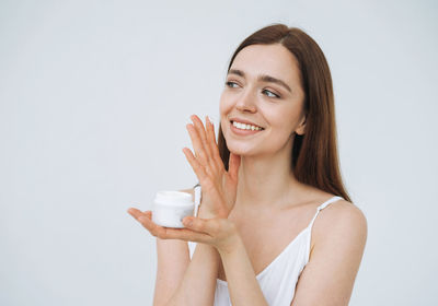 Beauty portrait of woman with dark long hair put day nourishing cream on clean fresh skin face