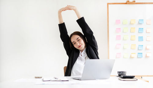 Portrait of young woman using mobile phone while sitting on table