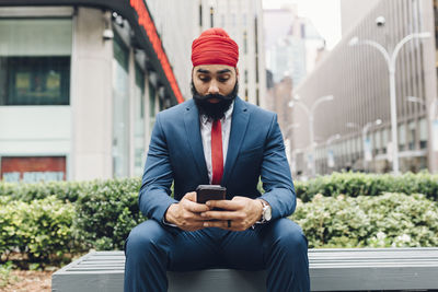 Indian businessman sitting in manhattan, using smartphone