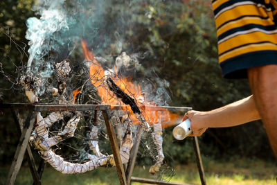 Midsection of man with arms raised on barbecue