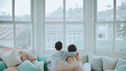 Rear view of couple looking through bay window