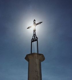Low angle view of weather vane against blue sky