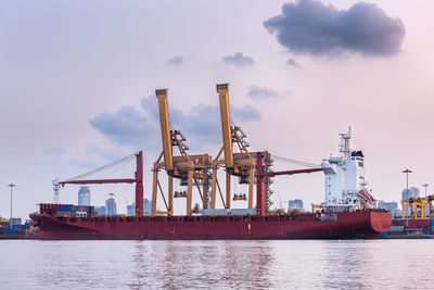 Cranes at commercial dock against sky