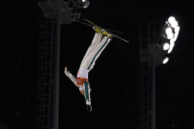 Upside down image of man hanging against black background