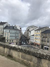 Buildings by canal against sky in city
