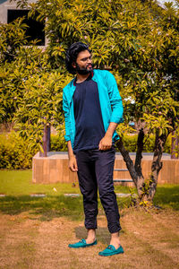 Young man looking away while standing against plants