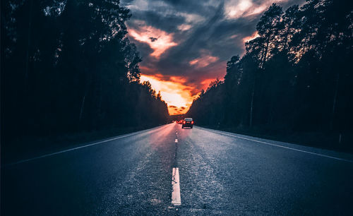 Road amidst trees against sky during sunset