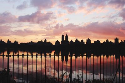 Silhouette trees by lake against sky during sunset