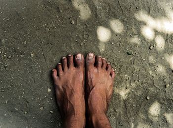 Low section of person standing on sand