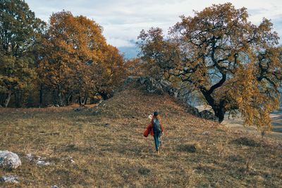 Rear view of man walking on field during autumn