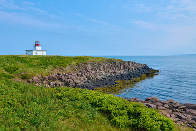 Lighthouse by sea against sky