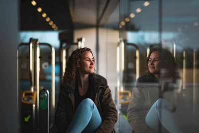 Smiling young woman looking through window