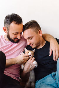 Gay couple playing with kitten.